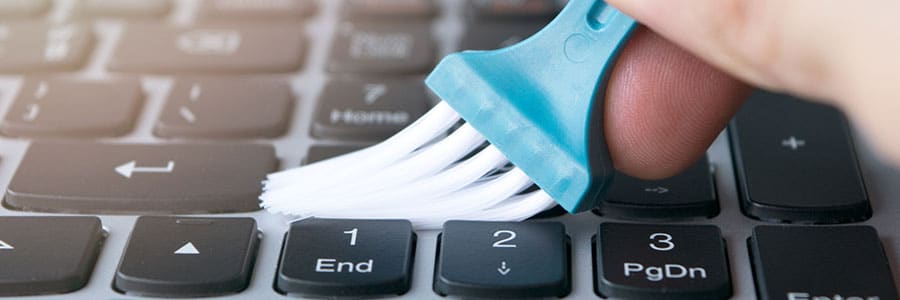 Person cleaning keyboard with a brush