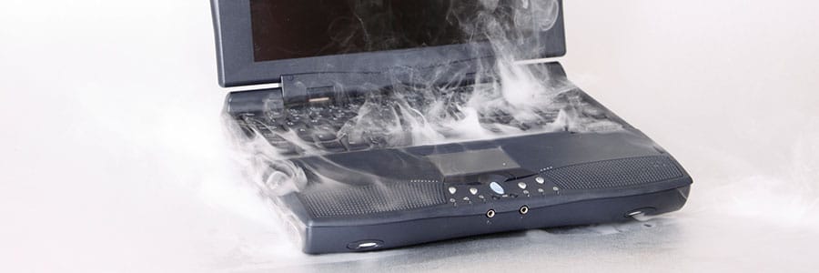 Old laptop that has smoke coming out of it