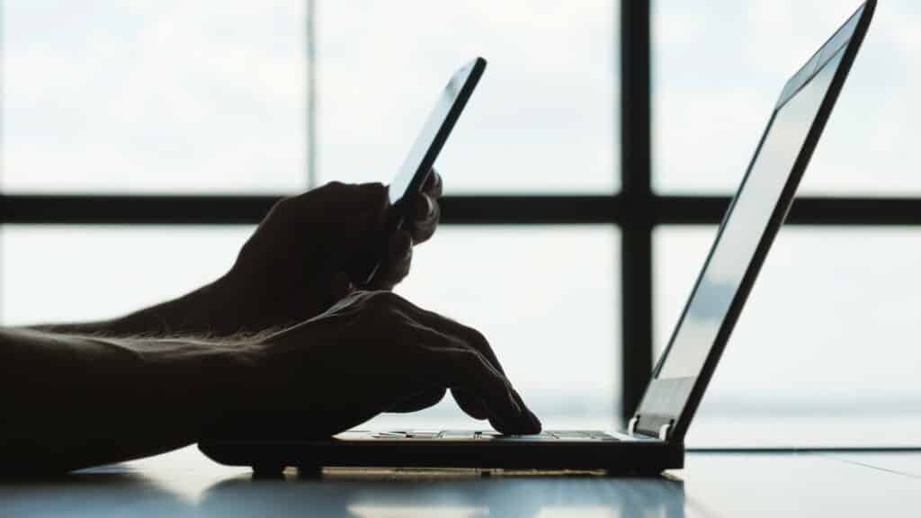 Person working on their phone and laptop