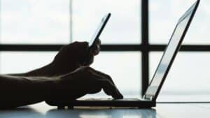 Person working on their phone and laptop