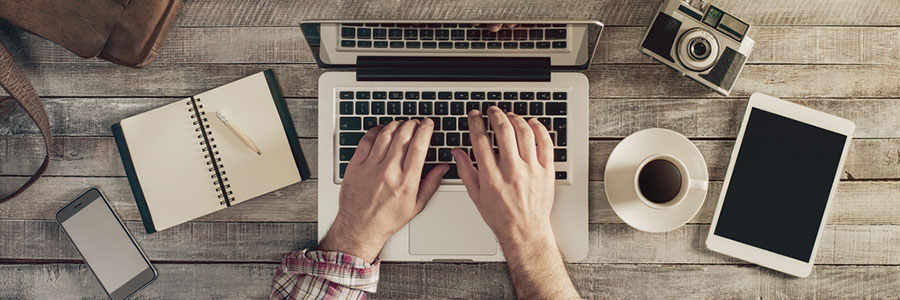 Person typing on their laptop with other stuff on the table