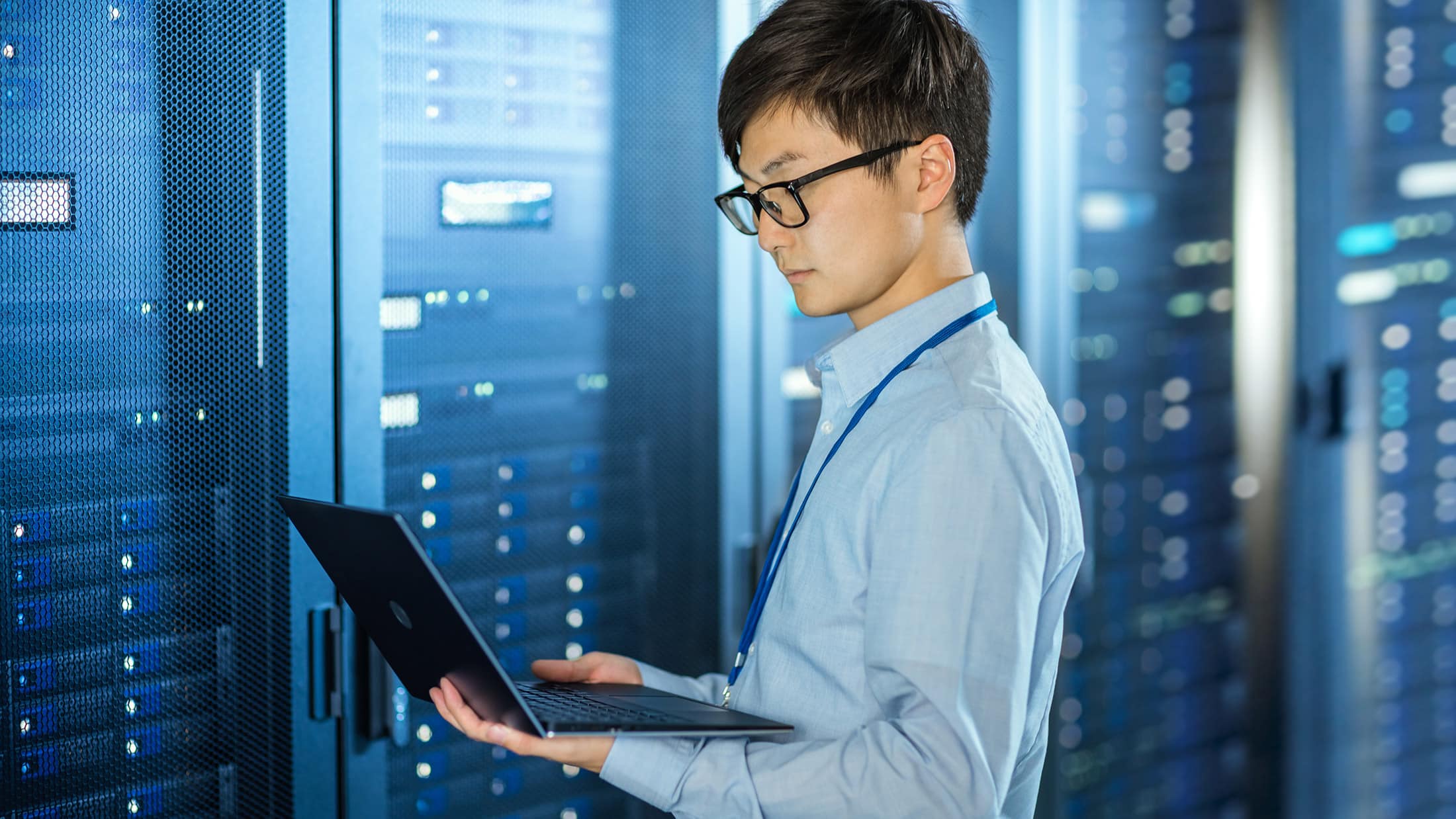 IT expert working on a laptop in a server room