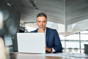 bank manager looking at laptop and updating his cybersecurity in banking policy